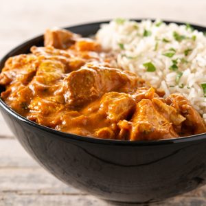 Indian butter chicken in black bowl on wooden table